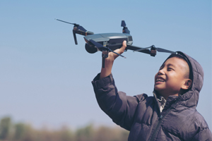 Young boy outside holding drone above his head